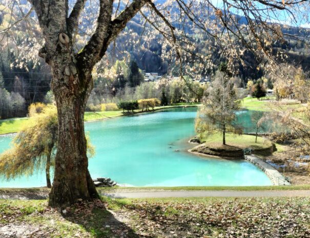 Lac de Bozel en automne, entouré d’arbres aux couleurs dorées et orangées.